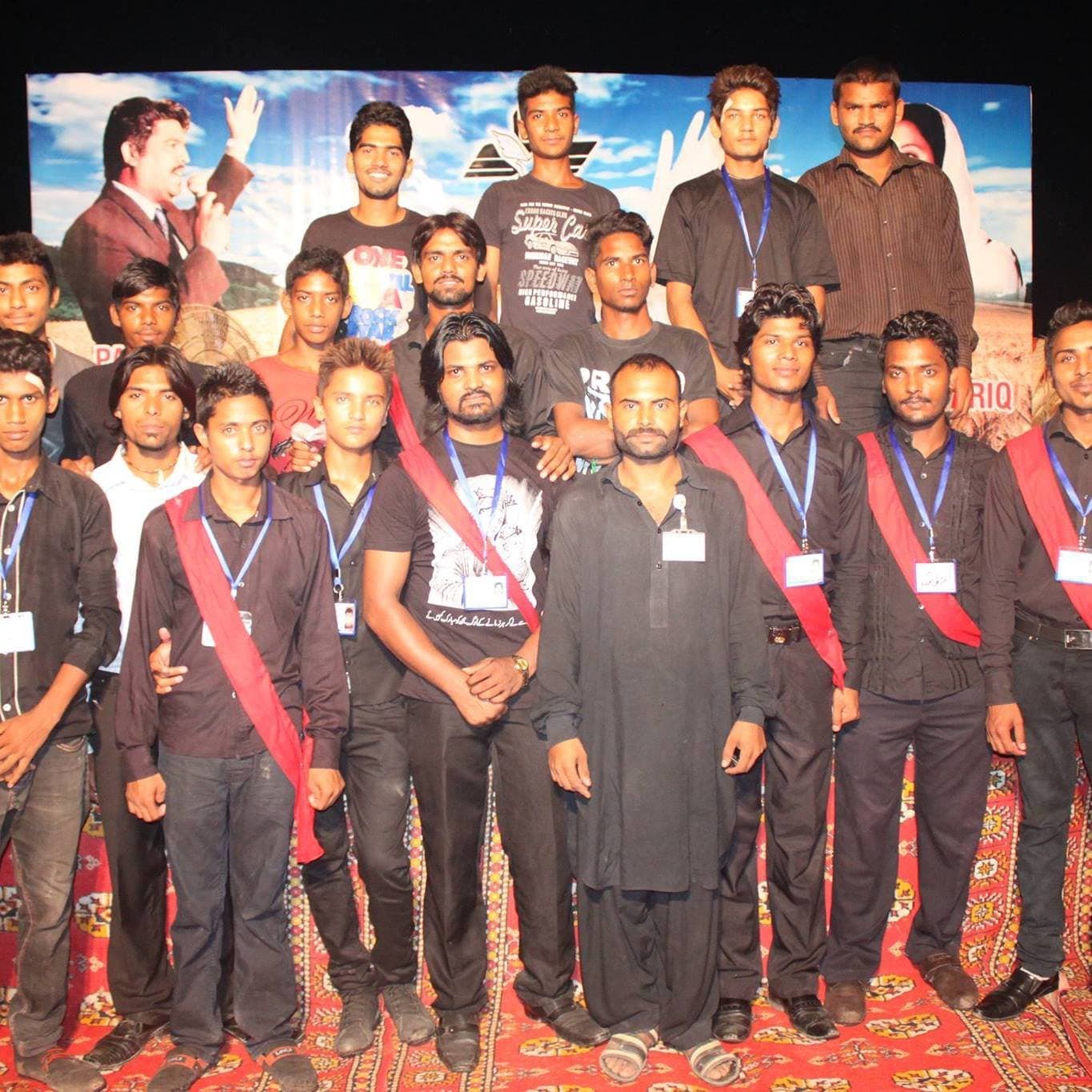 Young men from the church serve team in red sashes, gathered on stage