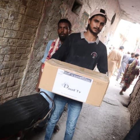 A volunteer carrying a box of supplies down a narrow lane