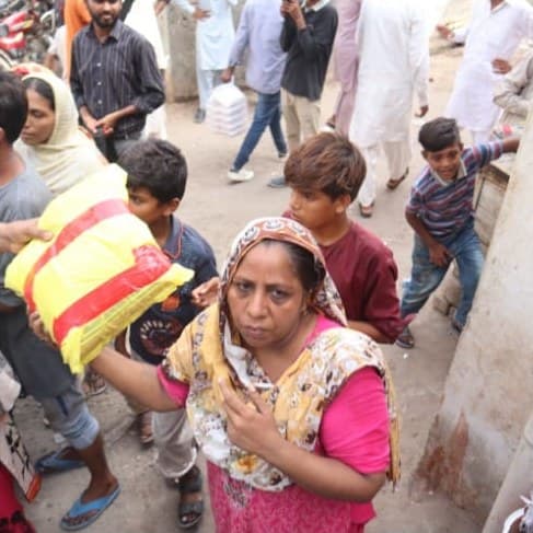 A woman carrying a bag of flour through the crowd