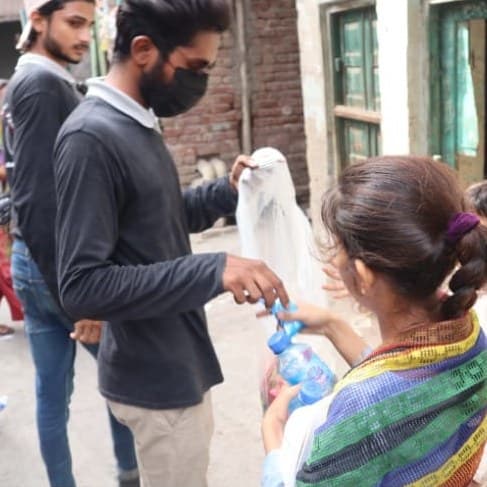 A volunteer handing a bottle of water to a woman