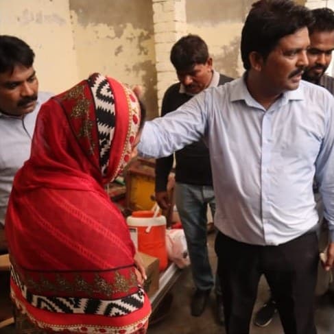 A church leader praying over a woman during a relief visit