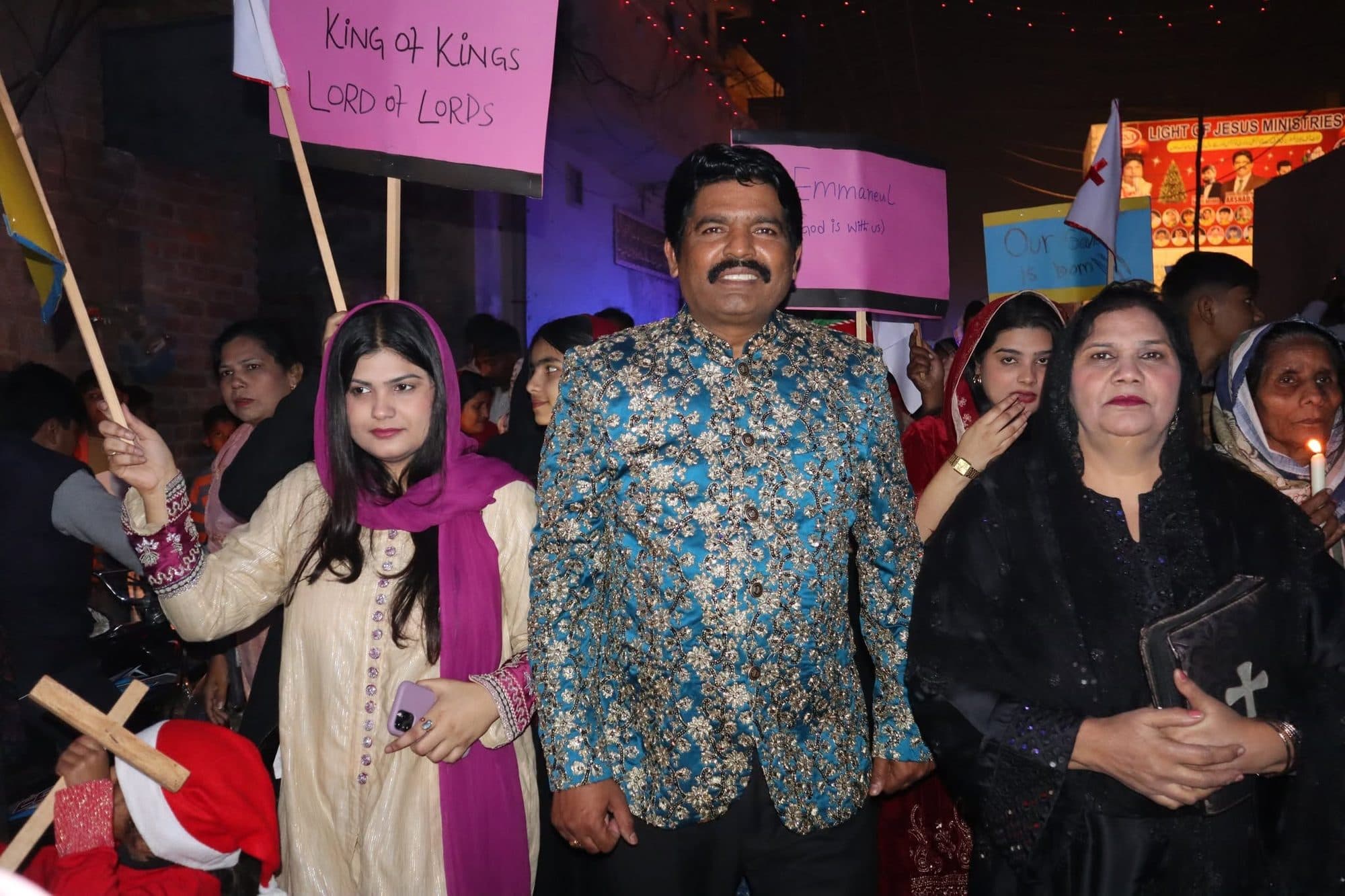 Pastor Arshad Sadiq leading the Christmas procession with signs reading King of Kings and Emmanuel
