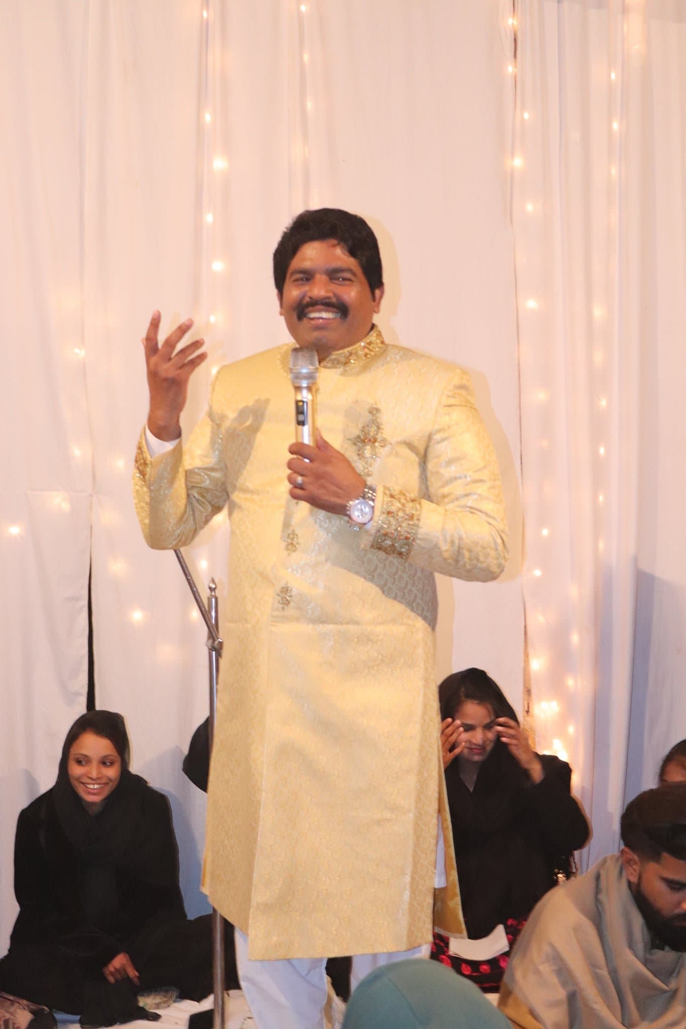 Pastor Arshad Sadiq laughing as he speaks at an evening celebration