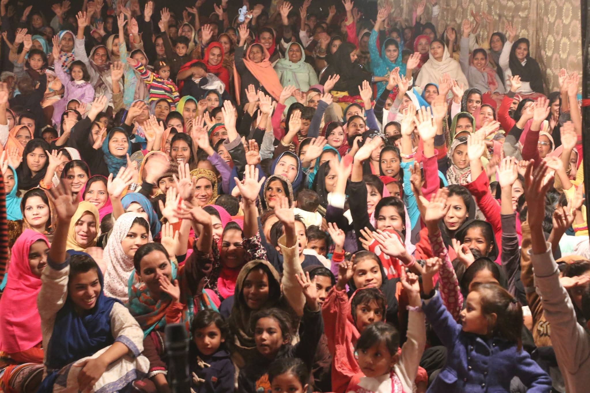 Women and children smiling and waving at a church gathering