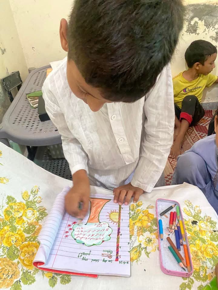 A boy colouring in his Sunday school copy